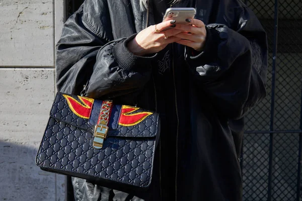 Vrouw met Gucci zwarte leren tas met rode en gele vlammen op zoek naar smartphone voor Etro modeshow, Milaan Fashion Week straatstijl — Stockfoto