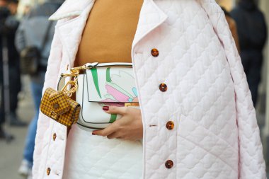 Fendi defilesinden önce soluk pembe ceketli ve Fendi çantalı bir kadın, Milan Moda Haftası tarzı.