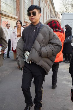 Fendi defilesinden önce gri yastıklı ceket ve güneş gözlüklü bir adam, Milan Moda Haftası tarzı.