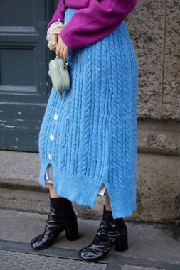 Reshake defilesinden önce mavi yün etekli ve mor kazaklı kadın, Milan Moda Haftası tarzı.