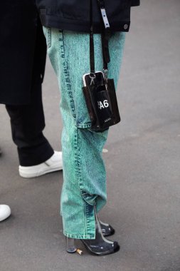 Marco de Vincenzo moda defilesinden önce turkuaz pantolonlu ve A6 siyah çantalı bir kadın, Milan Moda Haftası tarzı.