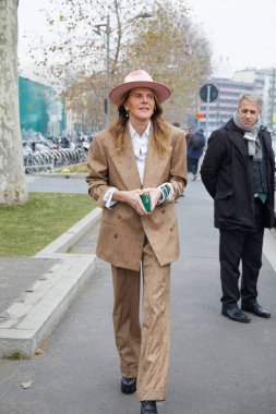 Gucci moda defilesinden önce bej ceketli, pantolonlu ve pembe şapkalı Anna Dello Russo, Milan Moda Haftası tarzı.