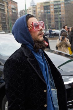 Gucci moda defilesinden önce siyah kadife ceketli ve pembe güneş gözlüklü bir adam, Milan Moda Haftası tarzı.