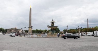 Obelisk ve Eyfel Kulesi manzaralı Concorde Meydanı. Paris 'te bulutlu bir yaz gününde karşıdan karşıya geçen insanlar.
