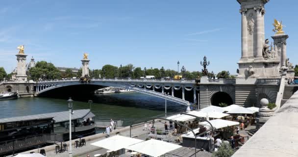 Paříž, Francie - 21. července 2017: Most Alexandre Iii s lidmi a turisty a kavárnou na břehu řeky za slunečného letního dne, modré nebe v Paříži, Francie. — Stock video