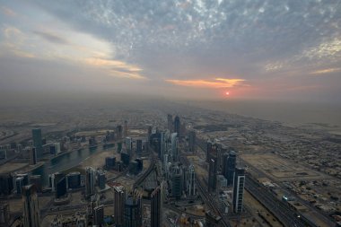 Dubai şehrinin yüksek açılı manzarası, gün batımında gökdelenler, bulutlu gökyüzü
