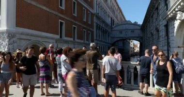 Venedik, İtalya 'da güneşli bir yaz gününde, insanların ve turistlerin geçtiği ve ünlü köprüye bakan köprü.
