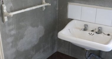 Eski banyo lavabosu ve soluk duvar manzarası.