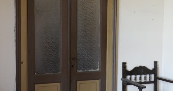 Призрак в белом платье проходит в комнате старого дома, стеклянная дверь — стоковое видео