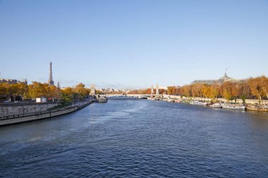 Paris 'te güneşli bir sonbahar gününde Eyfel Kulesi ve 3. Alexander Köprüsü' nün geniş açılı manzarasıyla Seine nehri manzarası