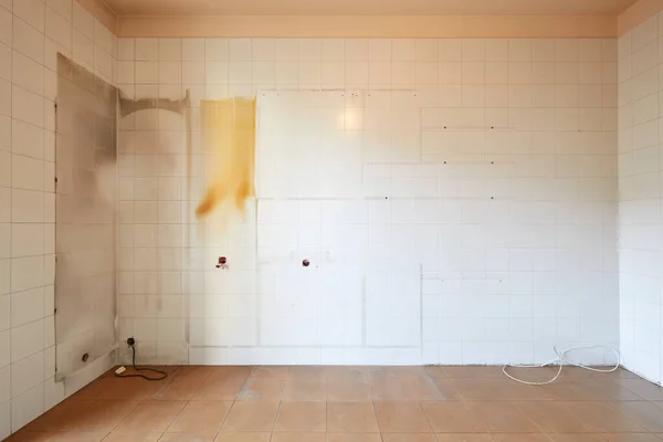 Empty, old kitchen interior with stained, tiled wall