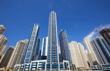 Dubai Marina yeni ve inşaat halinde güneşli bir günde gökdelenler, Dubai 'de açık mavi gökyüzü