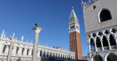 İtalya 'da güneşli bir günde aslan heykeli ve çan kulesi manzaralı San Marco meydanı.