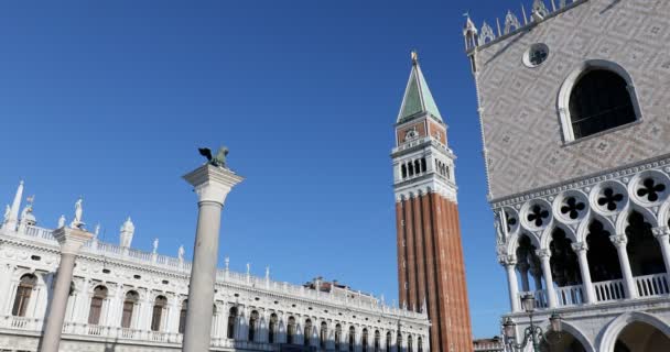 Площа Сан Марко з статуєю лева на колоні та дзвіницею нахилена у сонячний день в Італії. — стокове відео