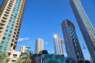 Dubai, BİRLİK ARAB EMIRATES - 23 Kasım 2019: Finansal bölgede palmiye ağaçları olan modern gökdelenler, Dubai 'de açık mavi gökyüzü 