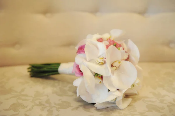 Traditioneller einfacher Hochzeitsstrauß mit weißen Orchideen und rosa Rosen vor beigem Hintergrund — Stockfoto