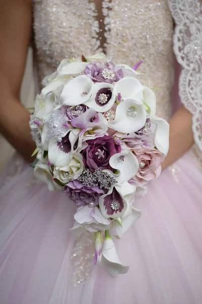 Невеста, держащая свадебный букет с калла-лилии с фиолетовыми акцентами и украшенный серебряными украшениями — стоковое фото