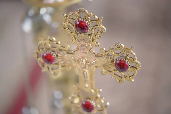 Ornate golden Orthodox cross, embellished with red gemstones, a dominant symbol for the Christian faith, in a Romanian church, Brasov, Romania