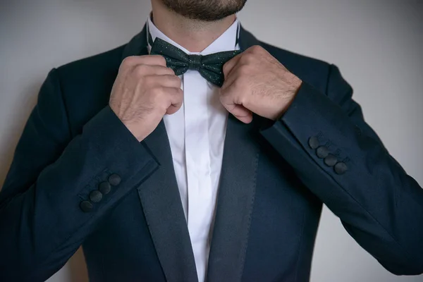 Young white Caucasian male putting his bow tie in order, and wearing formal, elegant attire — Stock Photo, Image