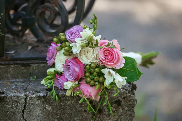 Różami oraz jagodami Bukiet ślubny, umieszczony na rustykalne, stary żelazne ogrodzenie pod zasępiać światło z niewyraźne tło — Zdjęcie stockowe
