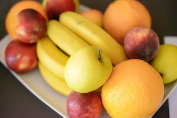 Oranges, pommes, bananes et pêches sur une assiette blanche, avec un accent sélectif — Photo