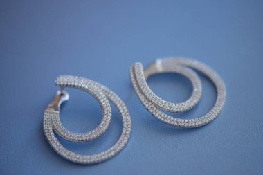 Mavi süet deri kumaş üzerine izole gümüş, beyaz altın, platin elmas küpe