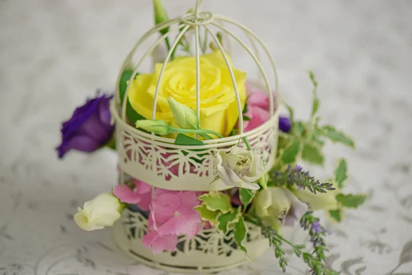 Mixed flowers arrangement with a large yellow rose in a vintage decorative birdcage as a wedding table centerpiece — Stock Photo, Image