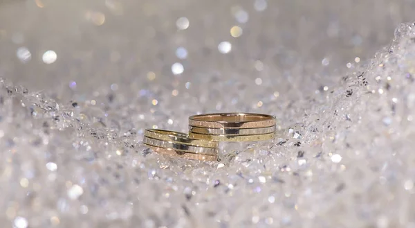 Combinando faixas de ouro do casamento em três cores posicionadas em um fundo chamativo feito de contas de cristal — Fotografia de Stock