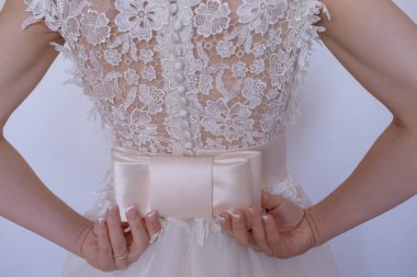 Onu geri bir büyük boy yay sabitleme işlemeli soluk pembe elbiseli genç beyaz gelin