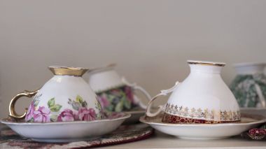 Eşsiz kemik çini porselen çay bardak ve tabaklar, bir raf üzerinde konumlandırılmış yıkanmış ve sonraki kullanım için temizlenmiş