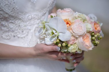 Elbise ve büyük beyaz orkide, pembe gül ve çilek buketi renkli bir yuvarlak pastel tutan genç beyaz gelin güzel giyen kırpılmış atış süslenmiş