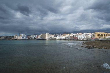 Dramatik bulutlu gökyüzü, düşük tide ve El Medano, Tenerife, Kanarya Adaları, İspanya şehir tarafındaki sakin dalgalar. El Madano doğru manzaralar iskelesinden, popüler su sporları için hedef, seyahat