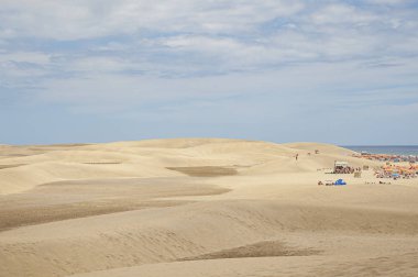 Adanın güney kıyısındaki Doğal Kum Tepeleri rezervinin güzel manzarası, turistlerin eğlendiği sahilin dar manzarası, Büyük Kanaryalar, Kanarya Adaları, İspanya