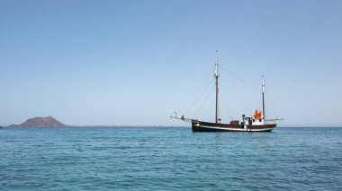 Corralejo, Fuerteventura, Kanarya Adaları, İspanya - 1 Ekim 2019: Los Lobos adasının panoramik manzarası ve durağan bir klasik yelkenli gemisi veya bir yelkenli gemisi, gündüz gezileri ve gezintiler gibi çalışır.