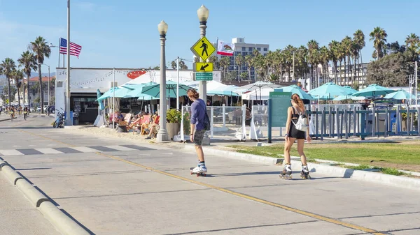 Los Angeles, Kaliforniya, ABD - 29 Eylül 2017: Genç insanlar, turistler veya yerliler, kaykay ve patenlerle Venedik sahilinden ünlü Santa Monica İskelesi 'ne boş yolun tadını çıkarıyorlar.