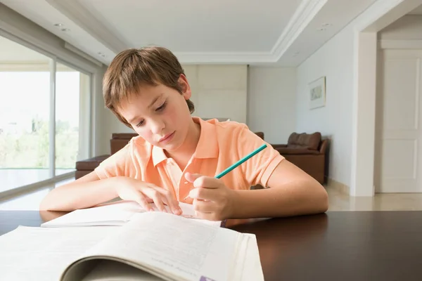 Мальчик делает домашнее задание за столом — стоковое фото