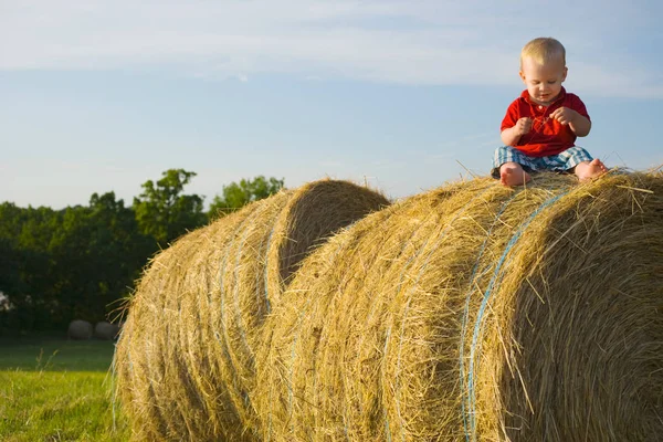 Boy sitting on haystack — Stock Photo, Image