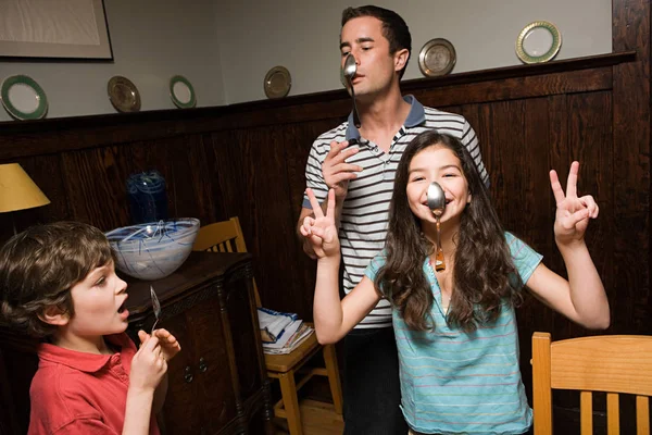 Padre e hijos colgando cucharas en la nariz —  Fotos de Stock
