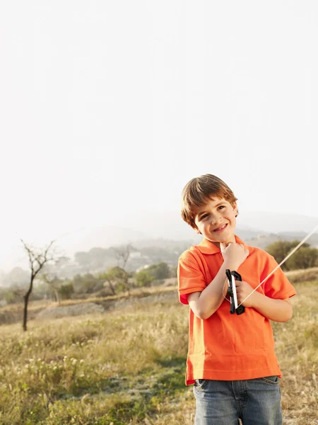 Niño sosteniendo cometa en el campo — Foto de Stock