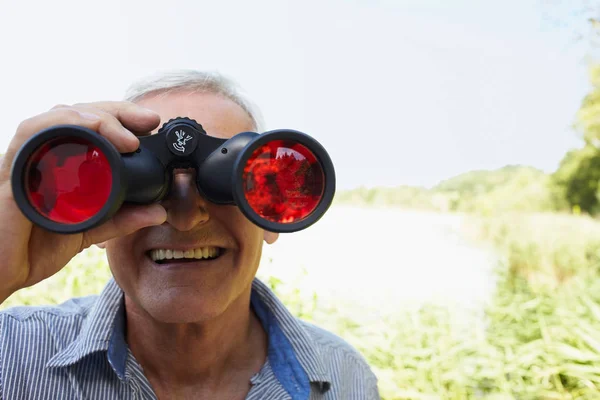 Homem sênior olhando através de vidro de campo — Fotografia de Stock