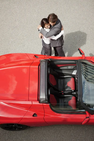 Pareja de negocios abrazando cerca de coche eléctrico — Foto de Stock