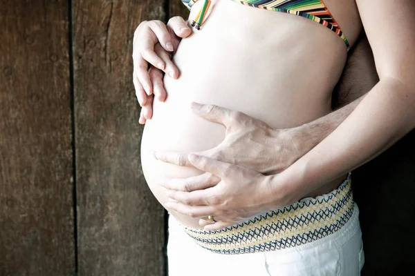 Casal segurando mulheres barriga grávida — Fotografia de Stock