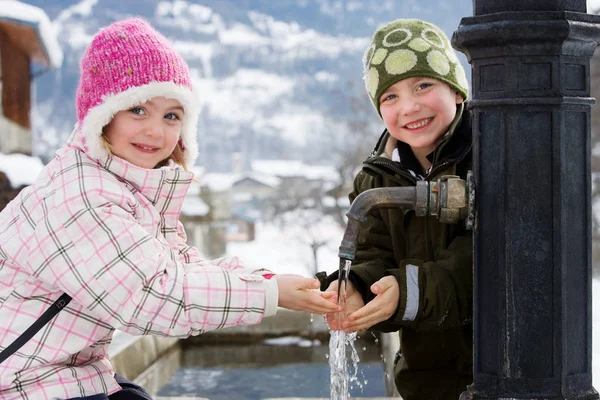 Jongen en meisje hand in hand onder kraan — Stockfoto