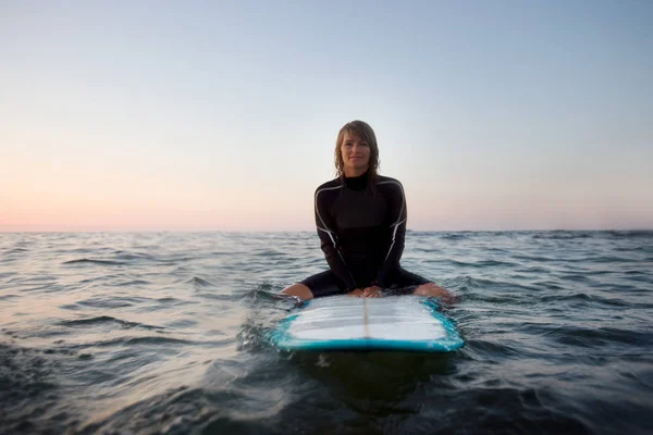 Femme assise sur la planche de surf — Photo