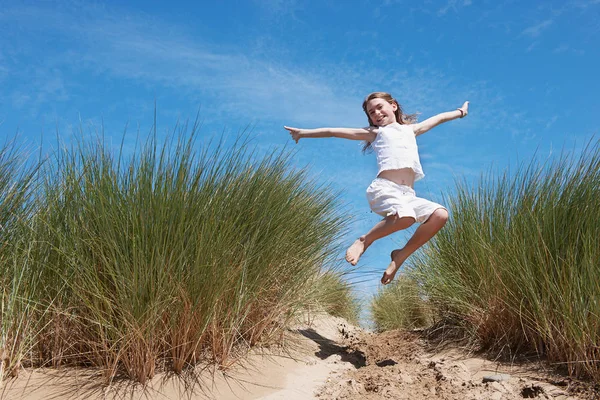 Giovane ragazza che salta in dune di sabbia — Foto Stock