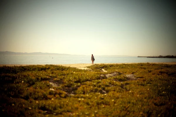 Giovane donna in piedi da sola sulla spiaggia — Foto Stock