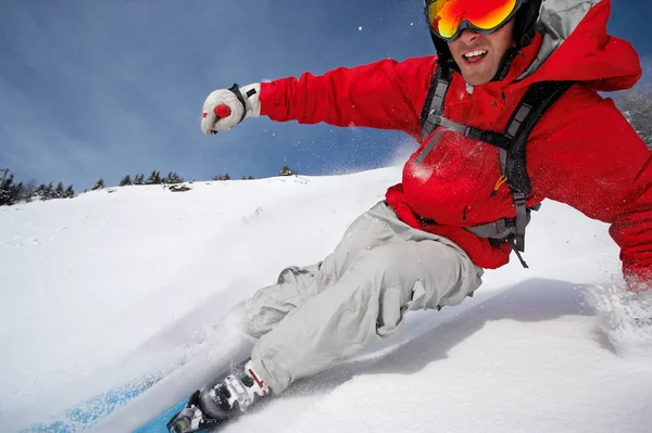 Mann lächelt beim Skifahren den Berg hinunter — Stockfoto