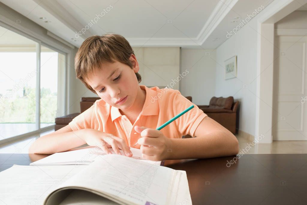 boy doing homework behind table