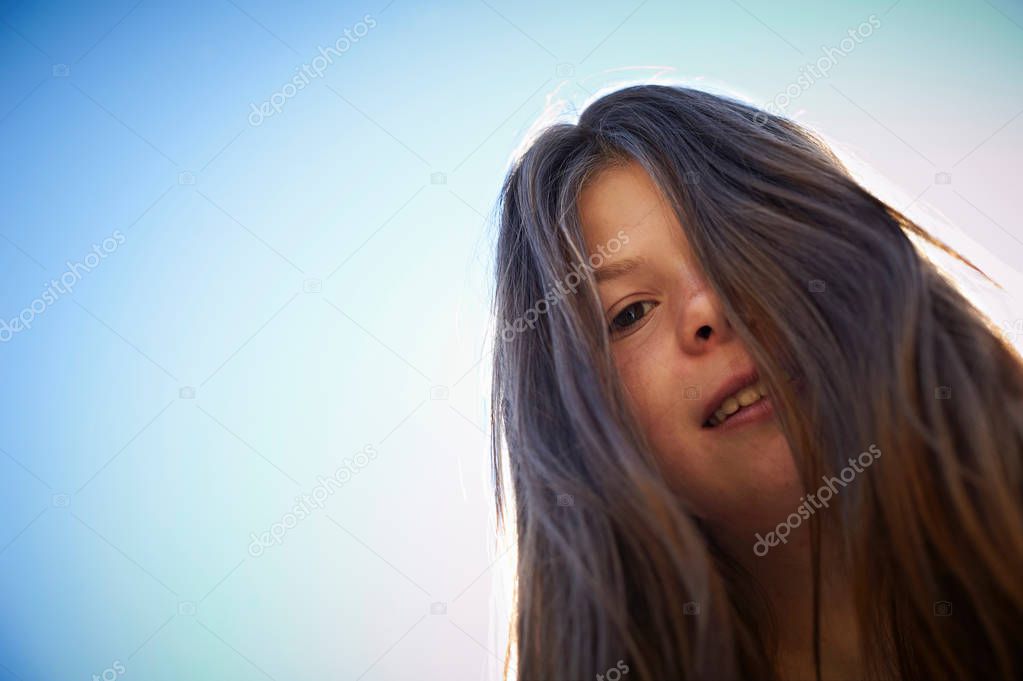 Teenage girl smiling against blue sky
