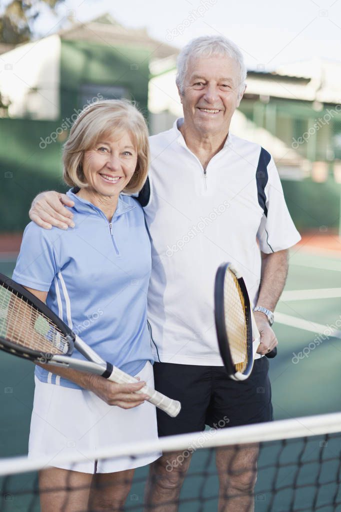 Older couple standing on tennis court